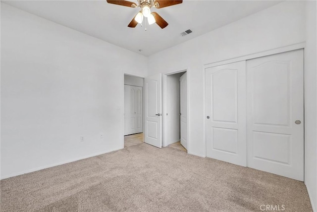 unfurnished bedroom featuring light colored carpet, a closet, and ceiling fan