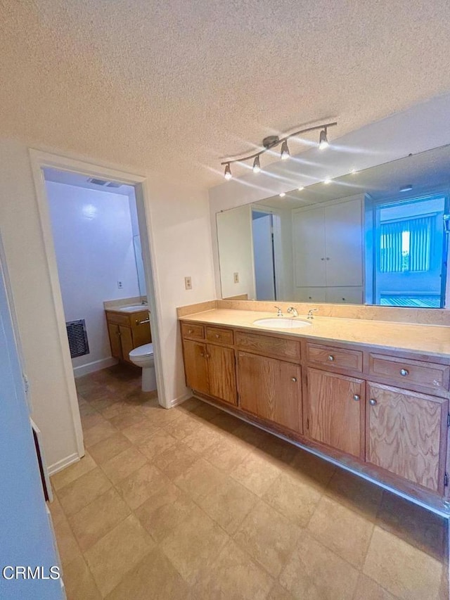 bathroom with vanity, a textured ceiling, and toilet