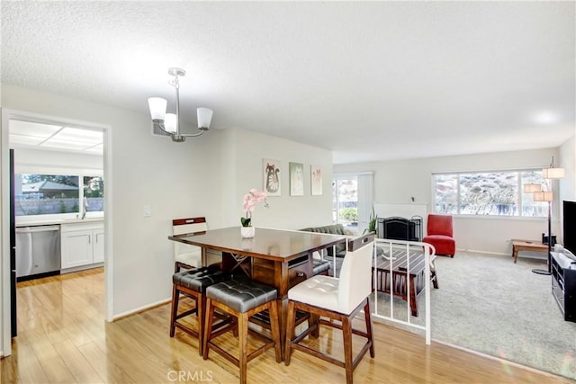 dining space with an inviting chandelier, a healthy amount of sunlight, sink, and light wood-type flooring