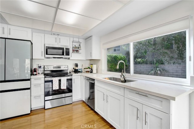 kitchen with white cabinetry, appliances with stainless steel finishes, sink, and light hardwood / wood-style floors