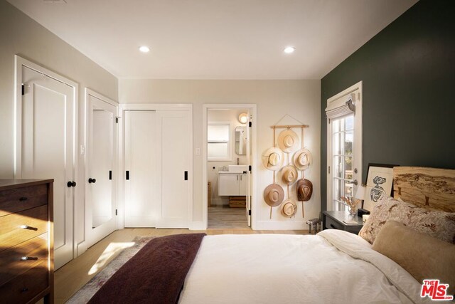 bedroom with ensuite bathroom and light hardwood / wood-style flooring