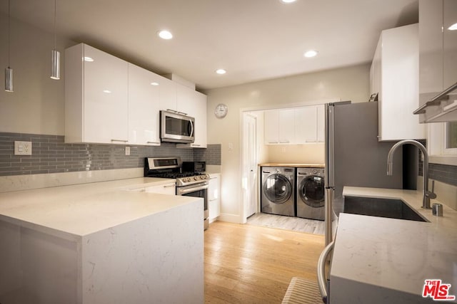 kitchen featuring separate washer and dryer, sink, white cabinetry, and appliances with stainless steel finishes