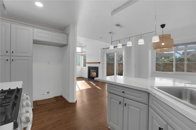 kitchen featuring white cabinetry, hanging light fixtures, dark hardwood / wood-style flooring, a wealth of natural light, and light stone countertops