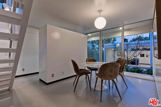 dining area with a wall of windows and concrete flooring