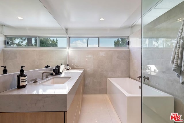 bathroom with a tub to relax in, plenty of natural light, vanity, and tile walls