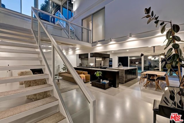 stairway featuring sink, a towering ceiling, and concrete flooring