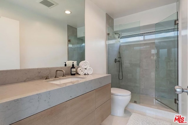 bathroom with a shower with door, vanity, tile patterned floors, and toilet