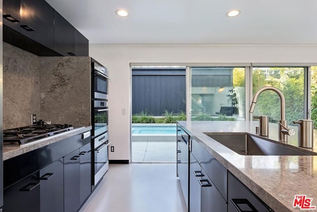 kitchen with tasteful backsplash, stainless steel gas stovetop, ventilation hood, and sink