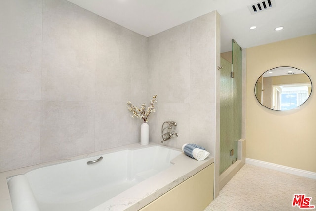 bathroom featuring independent shower and bath and tile walls