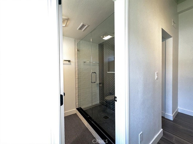 bathroom with a shower with shower door and a textured ceiling