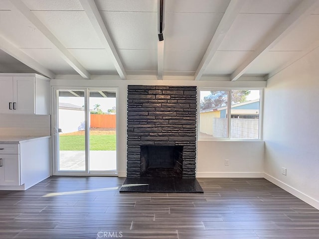 unfurnished living room featuring beam ceiling, dark wood-type flooring, and a fireplace