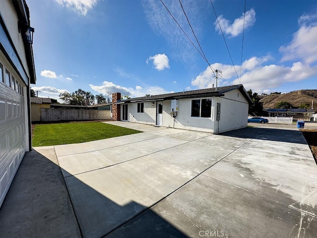 rear view of property with a mountain view, a yard, and a patio area