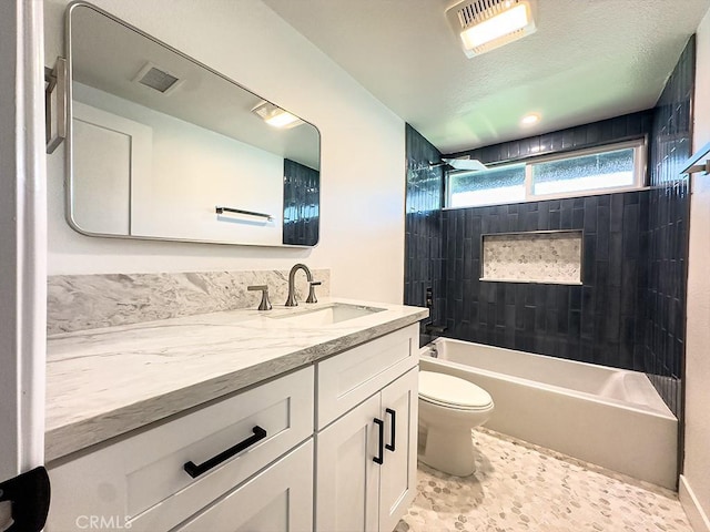 full bathroom featuring vanity, tiled shower / bath combo, a textured ceiling, and toilet