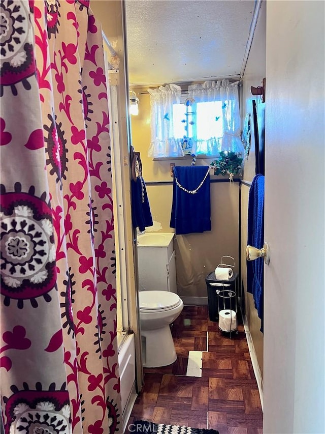 bathroom with parquet floors, toilet, bathing tub / shower combination, and a textured ceiling