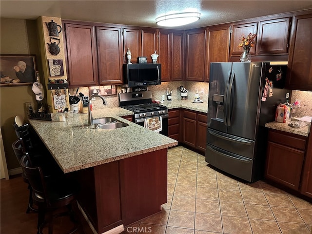 kitchen featuring appliances with stainless steel finishes, sink, light tile patterned floors, light stone counters, and kitchen peninsula