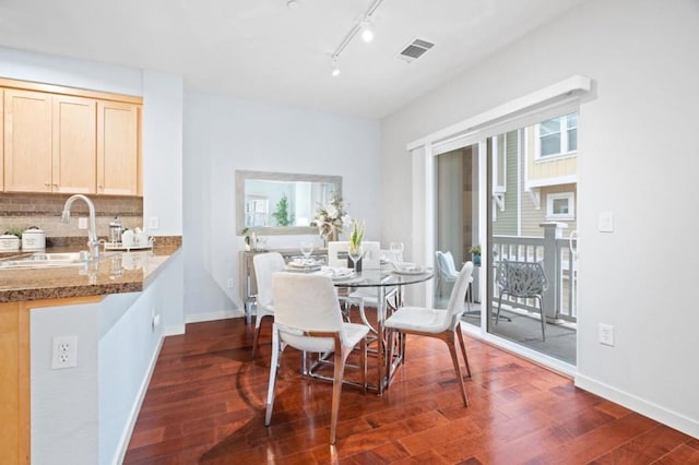 dining space featuring track lighting, dark hardwood / wood-style flooring, and sink