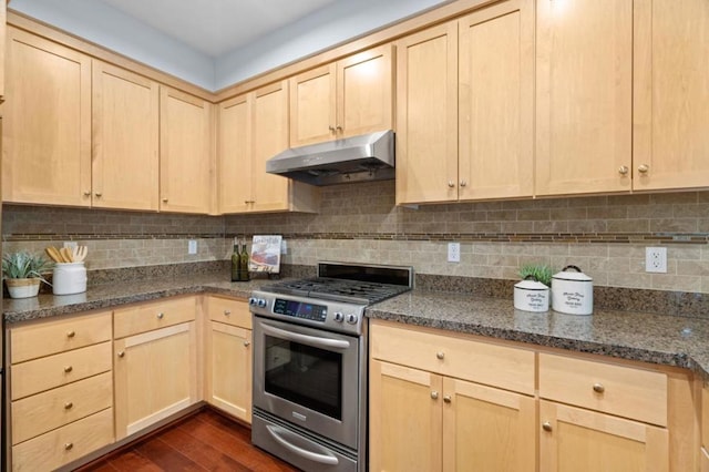 kitchen with stainless steel gas stove, tasteful backsplash, dark hardwood / wood-style flooring, dark stone counters, and light brown cabinets