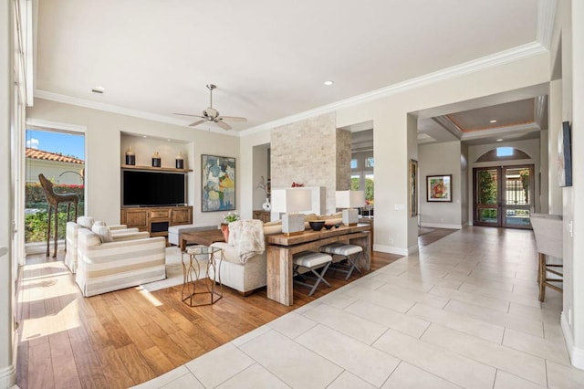 living room featuring ornamental molding, ceiling fan, and light wood-type flooring