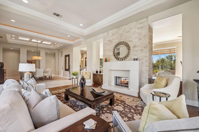 living room with crown molding, a large fireplace, wood-type flooring, and a tray ceiling