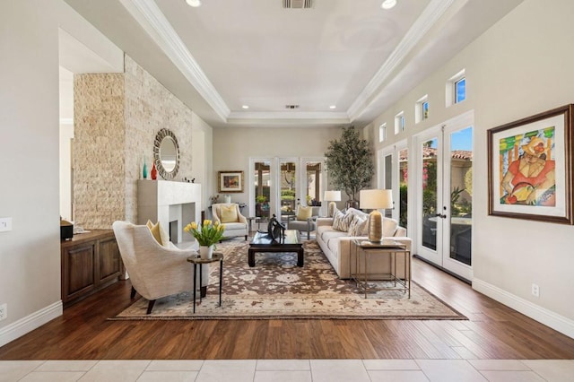 sitting room featuring french doors, ornamental molding, a tray ceiling, and tile patterned flooring