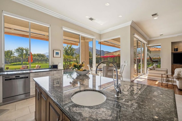 kitchen with crown molding, stainless steel dishwasher, sink, and dark stone countertops