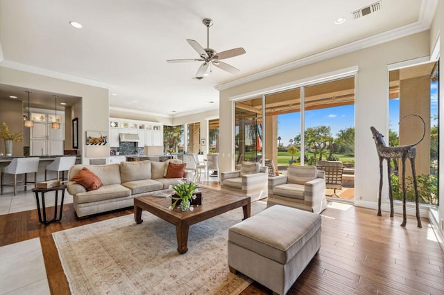 living room featuring wood-type flooring, ornamental molding, and ceiling fan