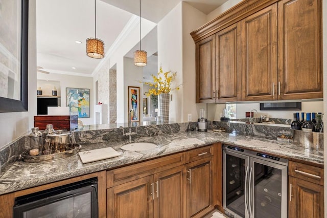 kitchen with wine cooler, sink, pendant lighting, and stone countertops