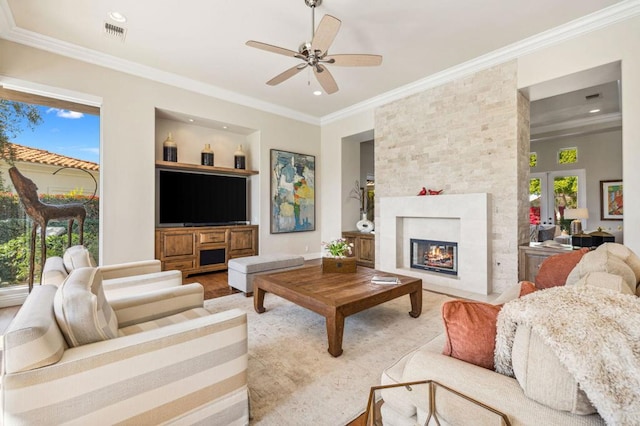 living room featuring built in shelves, a large fireplace, plenty of natural light, and ornamental molding