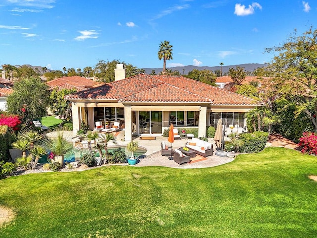 back of property featuring a mountain view, an outdoor hangout area, a yard, and a patio area