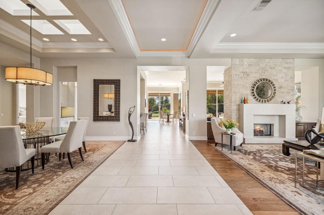 interior space featuring a tiled fireplace, crown molding, a raised ceiling, and light tile patterned floors