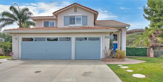 mediterranean / spanish house featuring a garage and a front lawn