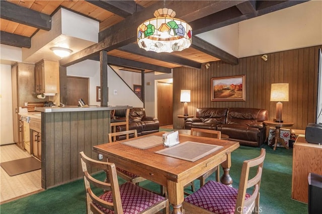 dining space with wooden ceiling, beam ceiling, carpet, and wood walls