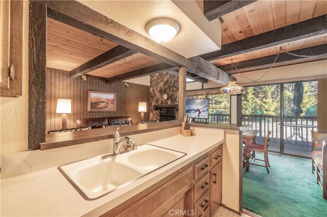 kitchen with sink, beam ceiling, wooden walls, and wooden ceiling