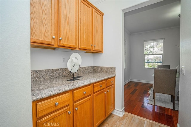 kitchen with ornamental molding, light stone countertops, and light hardwood / wood-style flooring