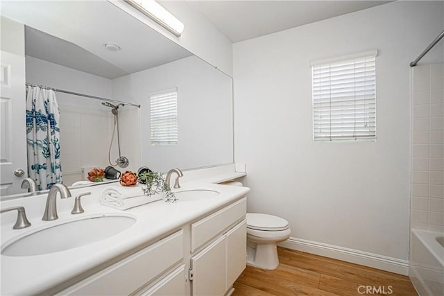 full bathroom with wood-type flooring, shower / tub combo, vanity, and toilet