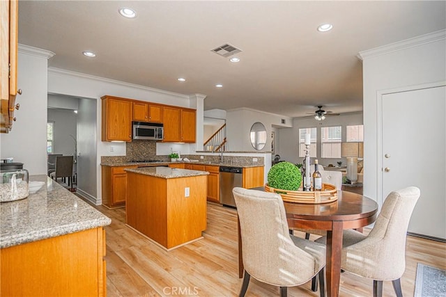 kitchen featuring light hardwood / wood-style flooring, stainless steel appliances, light stone counters, a kitchen island, and kitchen peninsula