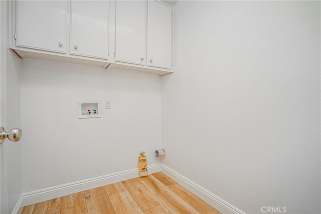 laundry area with hookup for a washing machine, cabinets, and light hardwood / wood-style flooring