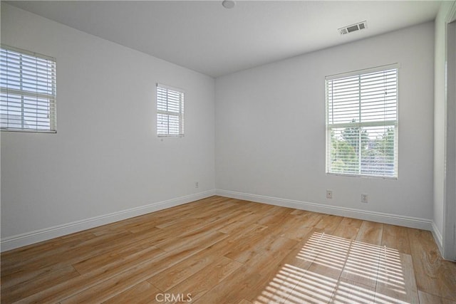 unfurnished room with a healthy amount of sunlight and light hardwood / wood-style flooring