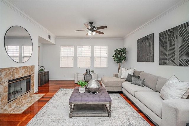 living room featuring a fireplace, a healthy amount of sunlight, dark hardwood / wood-style flooring, and ornamental molding