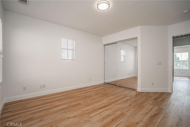 unfurnished bedroom with light hardwood / wood-style flooring and a closet