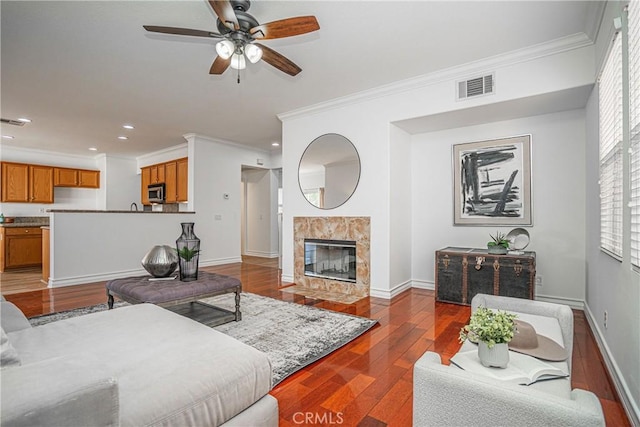 living room with ornamental molding, dark hardwood / wood-style floors, ceiling fan, and a fireplace