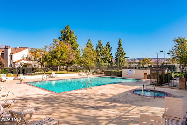 view of pool with a hot tub and a patio