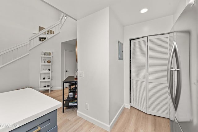 interior space featuring stainless steel fridge, electric panel, light hardwood / wood-style floors, and gray cabinetry