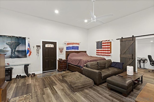 bedroom with hardwood / wood-style flooring, ceiling fan, and a barn door