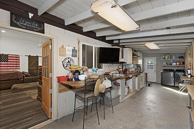 kitchen featuring white electric range, beamed ceiling, concrete floors, a barn door, and washer and clothes dryer