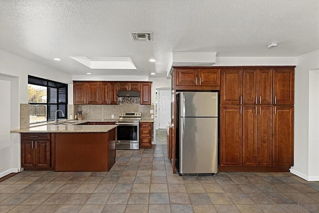 kitchen with sink, appliances with stainless steel finishes, backsplash, light stone counters, and kitchen peninsula