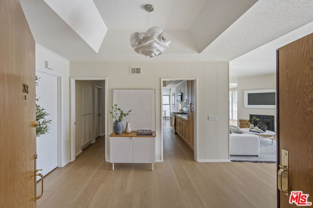 interior space with a tray ceiling and light wood-type flooring