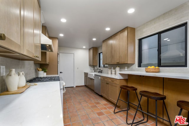 kitchen with extractor fan, sink, backsplash, a kitchen breakfast bar, and stainless steel dishwasher