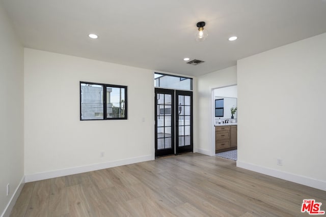 spare room featuring light hardwood / wood-style flooring and french doors