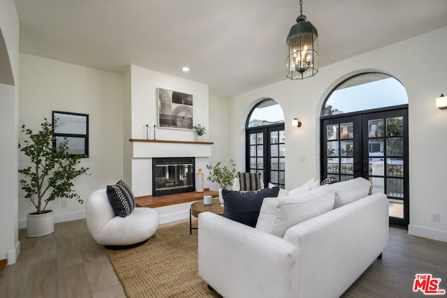 living room with an inviting chandelier, dark hardwood / wood-style flooring, and french doors